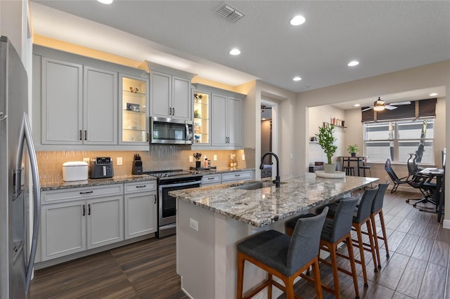 kitchen featuring a breakfast bar area, visible vents, decorative backsplash, appliances with stainless steel finishes, and a sink