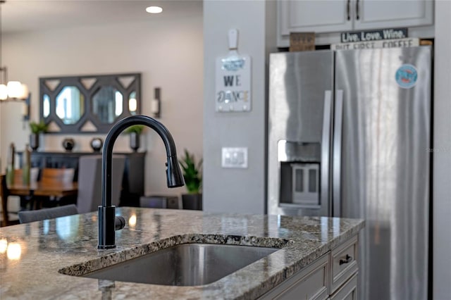 kitchen with recessed lighting, a sink, white cabinetry, stainless steel fridge with ice dispenser, and dark stone countertops