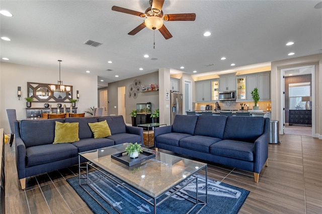 living room with dark wood-style floors, ceiling fan with notable chandelier, visible vents, and recessed lighting