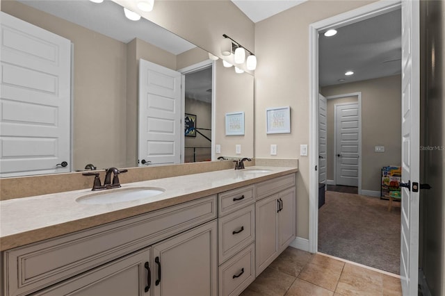 bathroom featuring double vanity, tile patterned flooring, a sink, and baseboards