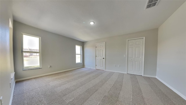 unfurnished bedroom with carpet flooring, visible vents, baseboards, and two closets