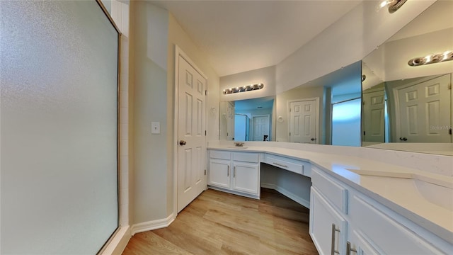 full bathroom with a shower with shower door, a sink, wood finished floors, baseboards, and double vanity