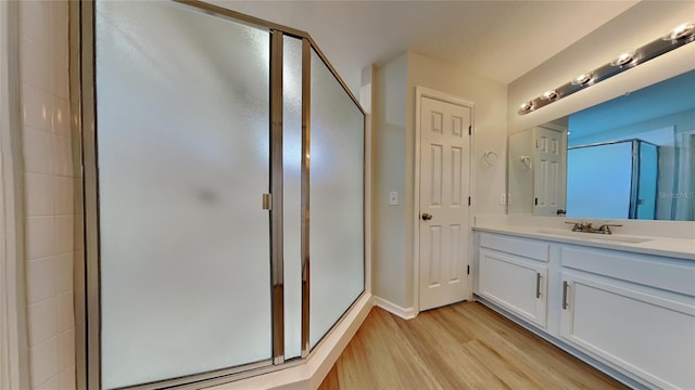 full bath with a shower stall, baseboards, wood finished floors, and vanity