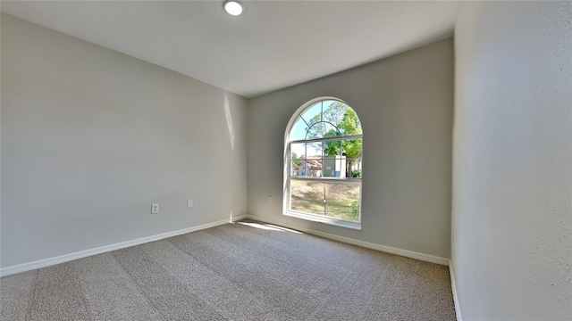 spare room featuring carpet and baseboards