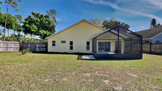 rear view of property featuring glass enclosure, a fenced backyard, a yard, and stucco siding