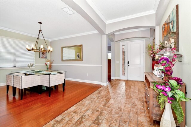 2541 Shoal Bass Way, Kissimmee, FL 34746 - entrance foyer with an inviting chandelier, light wood-style flooring, visible vents, arched walkways, and ornamental molding