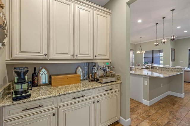 2541 Shoal Bass Way, Kissimmee, FL 34746 - kitchen featuring a sink, cream cabinets, light wood-style floors, ornamental molding, and hanging light fixtures