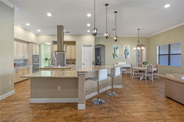 2541 Shoal Bass Way, Kissimmee, FL 34746 - kitchen featuring island exhaust hood, double oven, arched walkways, a large island with sink, and ornamental molding