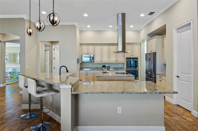 2541 Shoal Bass Way, Kissimmee, FL 34746 - kitchen featuring appliances with stainless steel finishes, ornamental molding, cream cabinetry, island range hood, and a large island with sink
