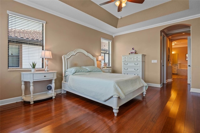 2541 Shoal Bass Way, Kissimmee, FL 34746 - bedroom featuring a tray ceiling, crown molding, dark wood-style flooring, baseboards, and arched walkways