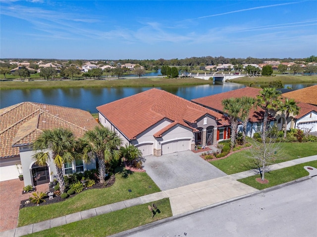 2541 Shoal Bass Way, Kissimmee, FL 34746 - view of front of house featuring a water view, an attached garage, driveway, a tiled roof, and a front yard