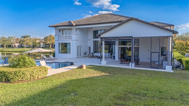 back of house with a balcony, a patio area, a lawn, and a sunroom