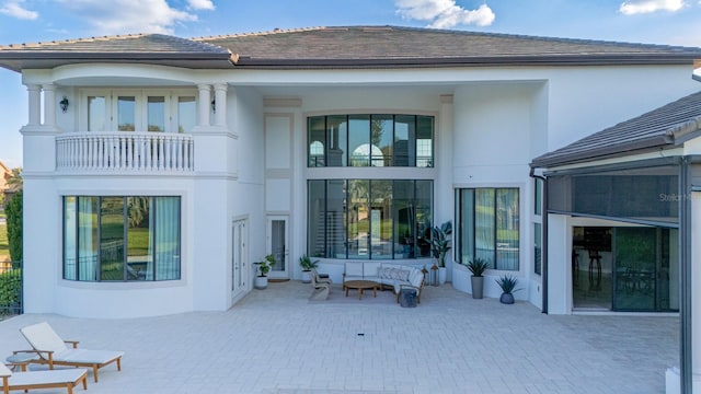 rear view of property with a patio, a tile roof, a balcony, and stucco siding