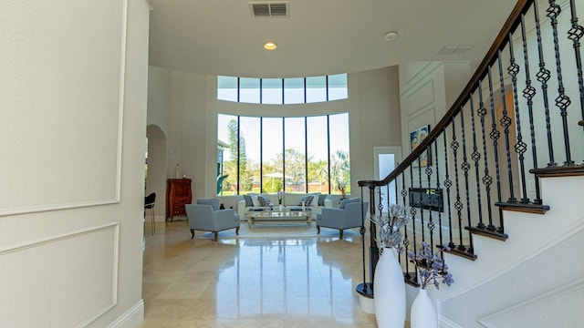 interior space with visible vents, arched walkways, a towering ceiling, stairs, and recessed lighting