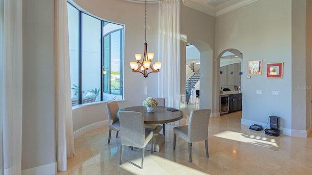 dining area featuring beverage cooler, crown molding, arched walkways, and baseboards