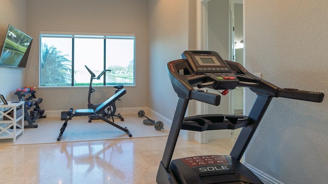 exercise room featuring tile patterned flooring and baseboards