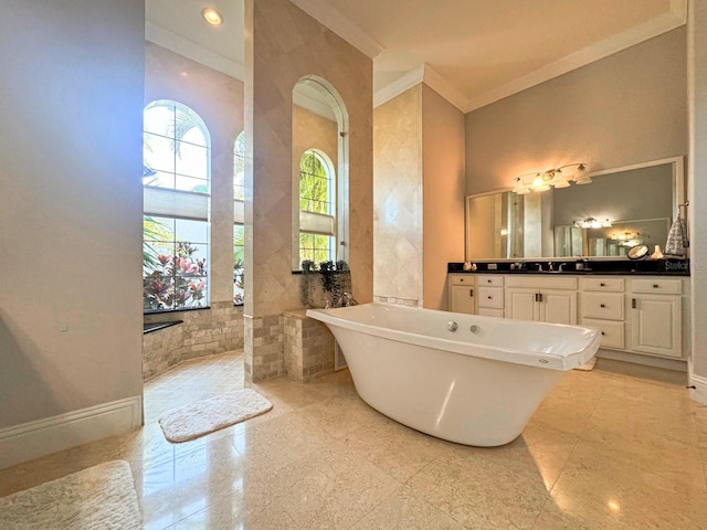 bathroom featuring baseboards, a soaking tub, ornamental molding, vanity, and tile walls