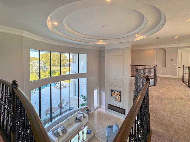 interior space featuring baseboards, a tray ceiling, a glass covered fireplace, and ornamental molding