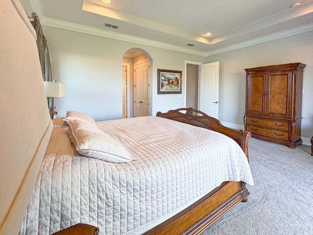 bedroom featuring carpet floors, a tray ceiling, visible vents, and arched walkways