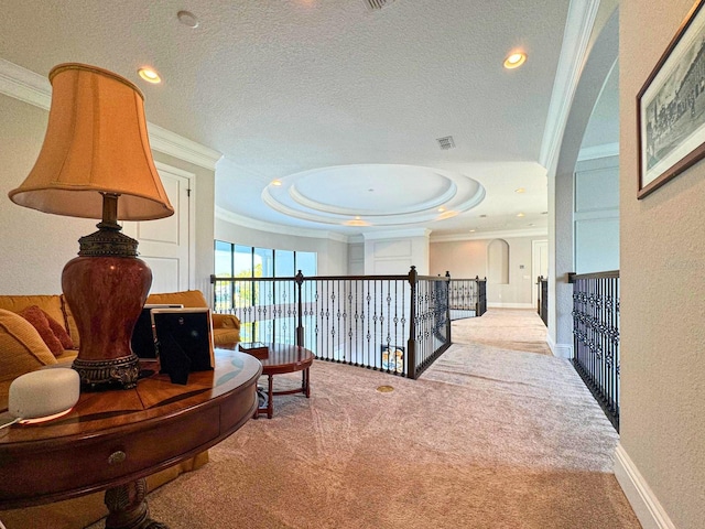 hall featuring a textured ceiling, carpet floors, baseboards, a raised ceiling, and crown molding