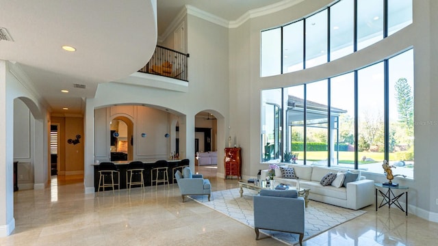 living area featuring baseboards, arched walkways, ornamental molding, marble finish floor, and recessed lighting