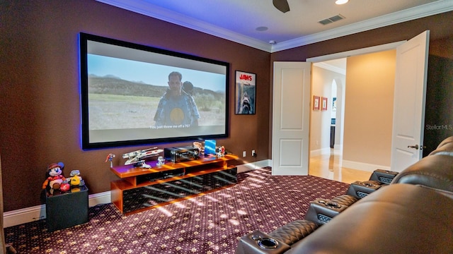 carpeted home theater featuring visible vents, crown molding, and baseboards