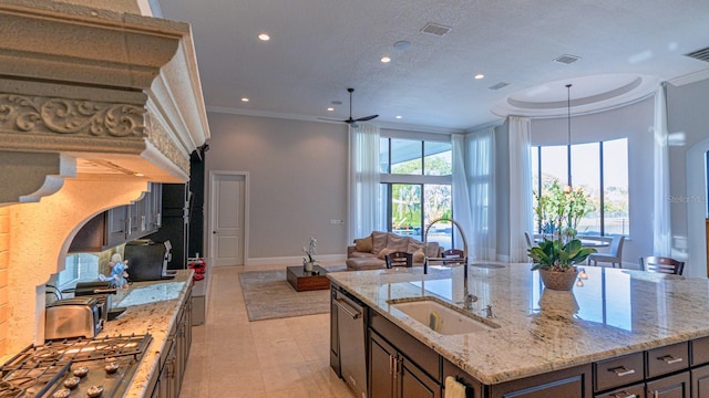 kitchen with crown molding, appliances with stainless steel finishes, open floor plan, and a sink