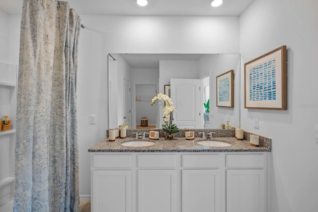 full bathroom with a closet, a sink, a shower with shower curtain, and double vanity