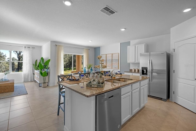 kitchen featuring stainless steel appliances, visible vents, stone countertops, a healthy amount of sunlight, and a sink