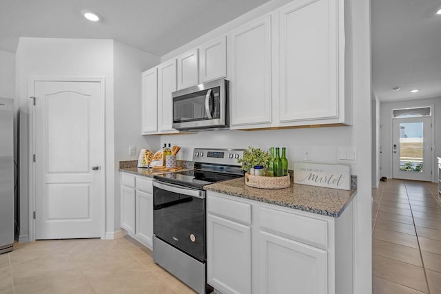 kitchen with appliances with stainless steel finishes, white cabinets, dark stone countertops, and recessed lighting