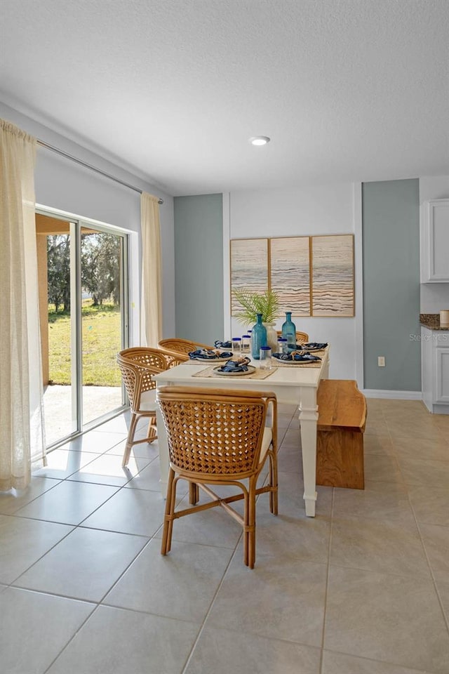 dining area featuring light tile patterned floors, a textured ceiling, and baseboards