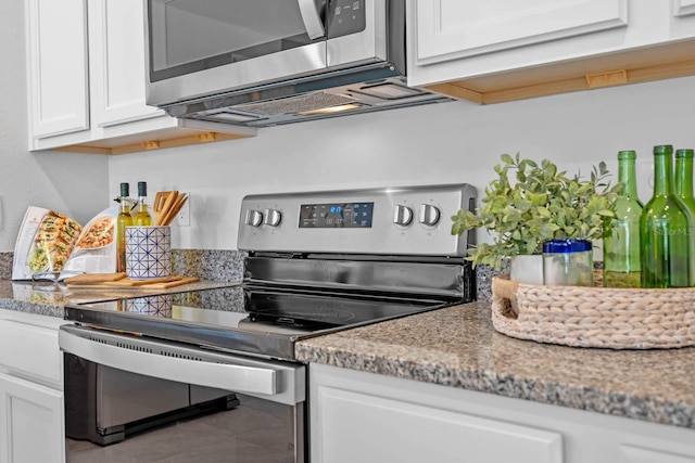 kitchen with light stone countertops, white cabinetry, stainless steel appliances, and tile patterned floors