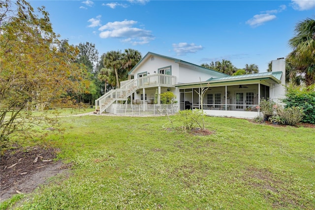 rear view of house with a yard, a sunroom, metal roof, ceiling fan, and stairs