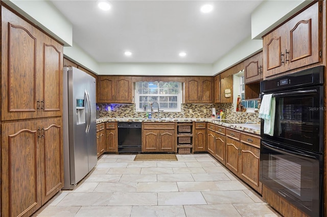 kitchen with black appliances, light countertops, tasteful backsplash, and a sink