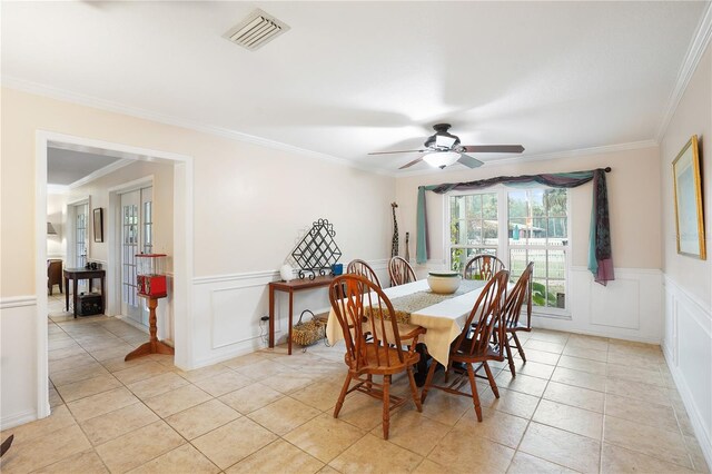 dining space featuring a wainscoted wall, crown molding, light tile patterned flooring, and visible vents