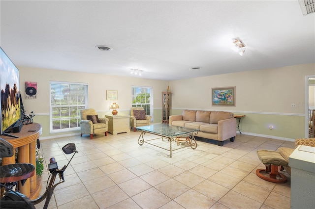 living room featuring light tile patterned floors, baseboards, and visible vents