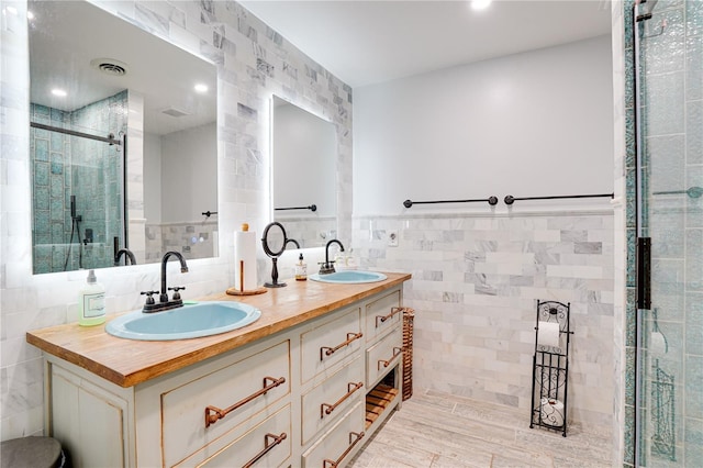 bathroom with tile walls, visible vents, a stall shower, and a sink