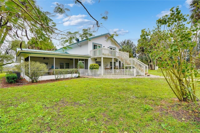 rear view of house with a ceiling fan, stairway, a yard, a sunroom, and metal roof