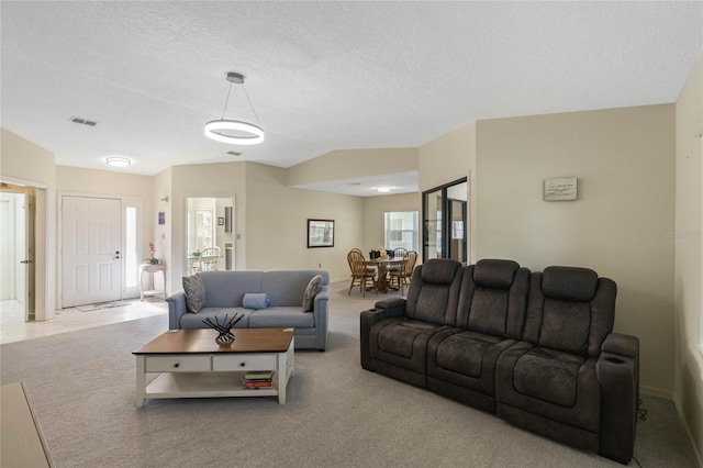 living area with visible vents, a textured ceiling, lofted ceiling, and carpet