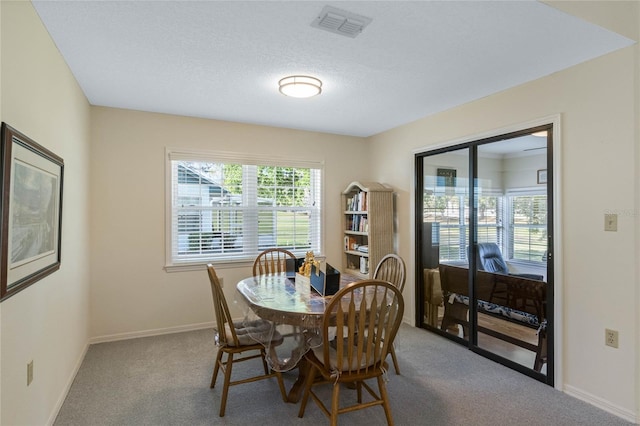 dining space with visible vents, carpet floors, a textured ceiling, and baseboards