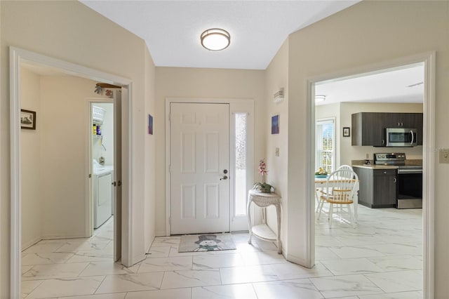 foyer entrance with washer / dryer, baseboards, and marble finish floor