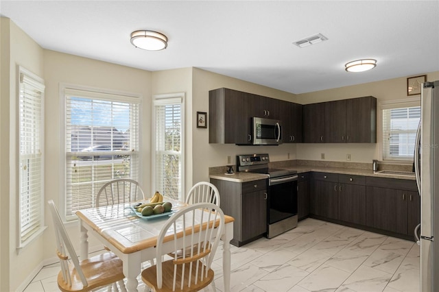 kitchen featuring visible vents, marble finish floor, appliances with stainless steel finishes, and dark brown cabinetry