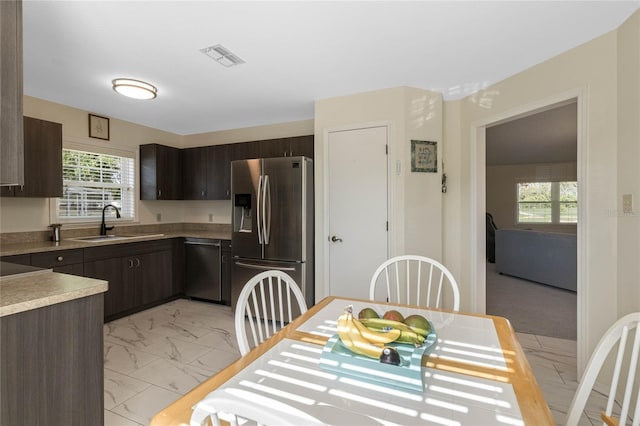 kitchen featuring marble finish floor, a sink, appliances with stainless steel finishes, light countertops, and dark brown cabinets