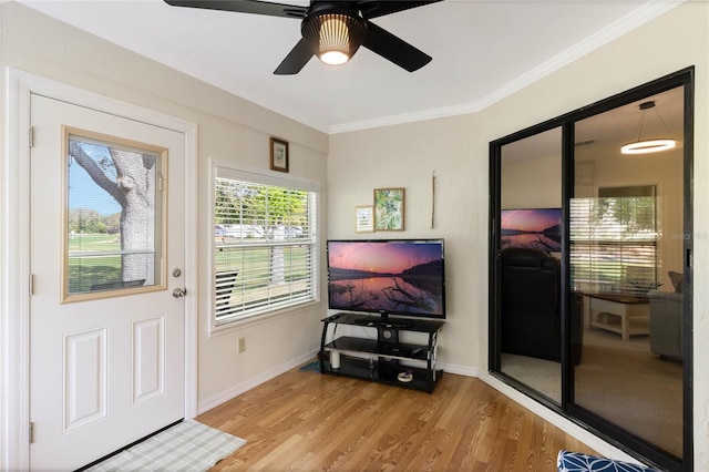 interior space featuring a ceiling fan, crown molding, wood finished floors, and baseboards