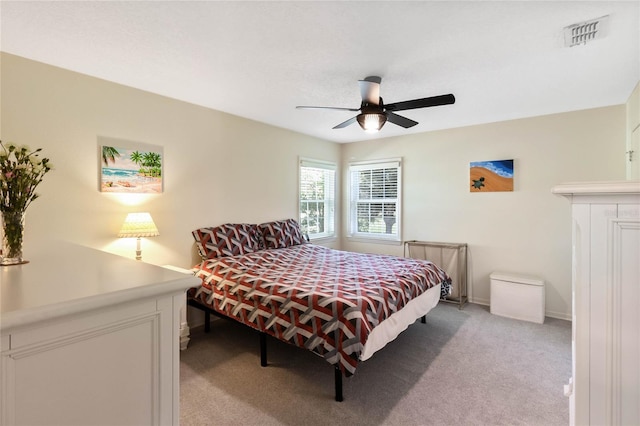 bedroom with baseboards, light colored carpet, visible vents, and ceiling fan