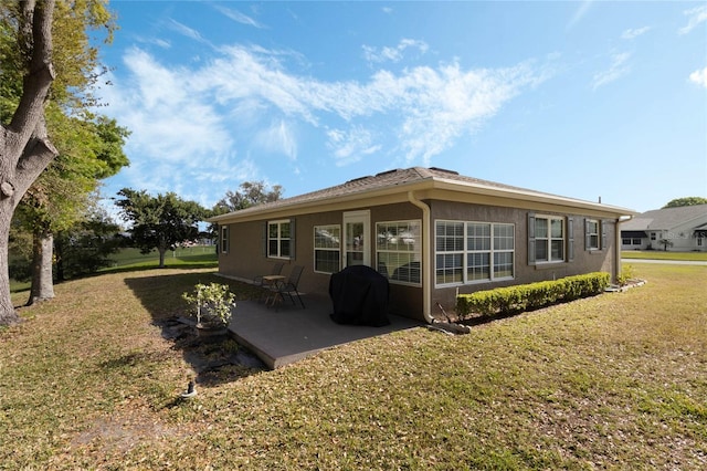 back of property with a patio area, stucco siding, and a yard