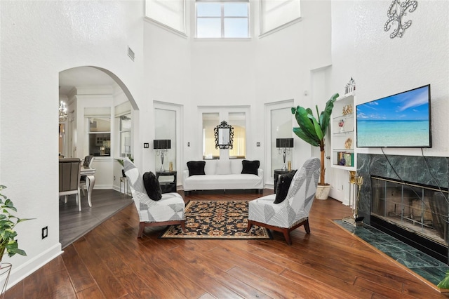 living area featuring hardwood / wood-style floors, baseboards, arched walkways, and a premium fireplace