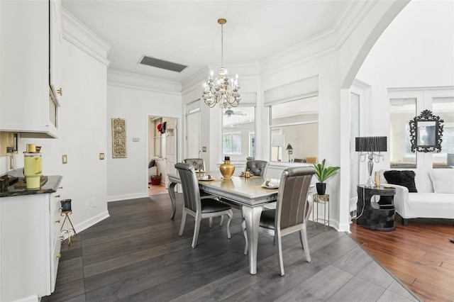 dining space featuring dark wood-style floors, arched walkways, a chandelier, and ornamental molding