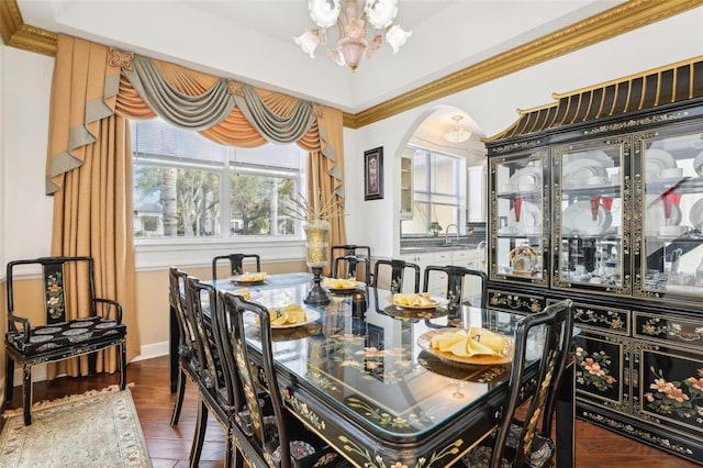 dining area featuring arched walkways, a notable chandelier, wood finished floors, and ornamental molding