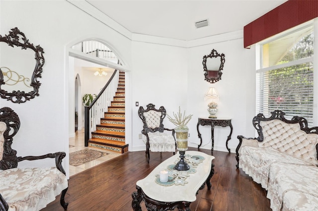 living area with visible vents, arched walkways, wood-type flooring, and ornamental molding